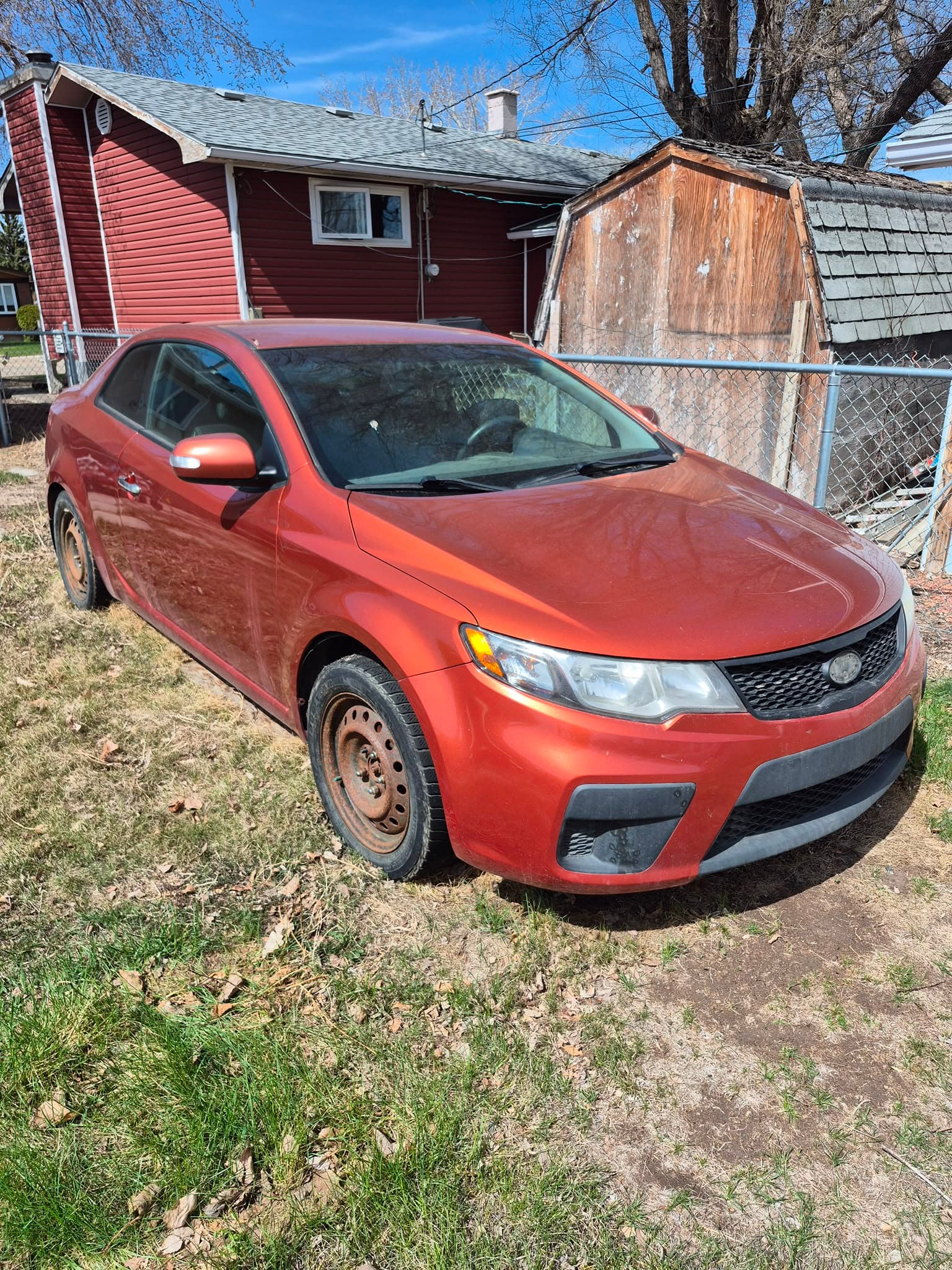Used red coupe ready to sell from a residential driveway